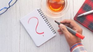 Question mark written in a note book in red ink.