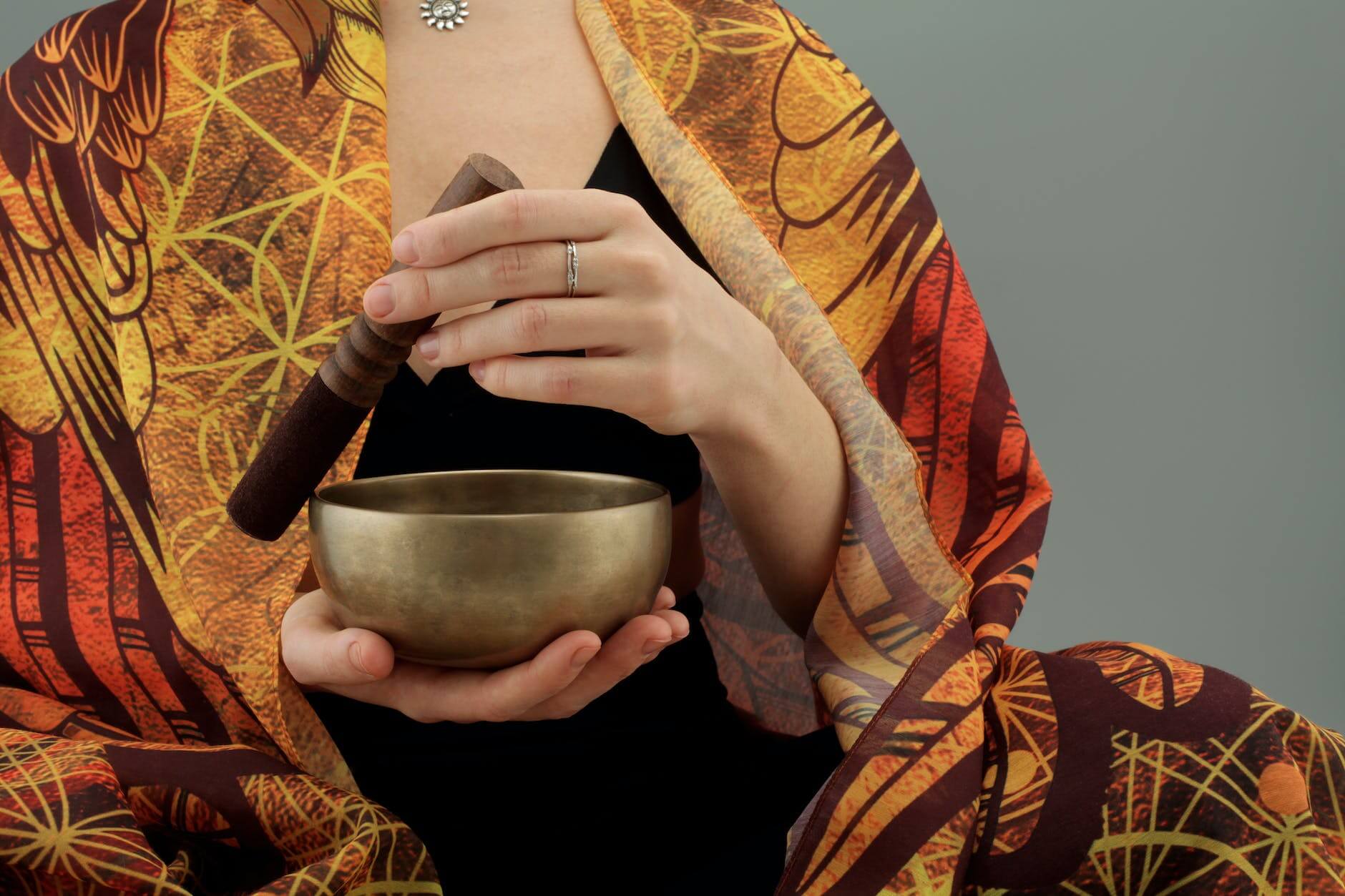 woman holding a wooden stick and a bronze bowl